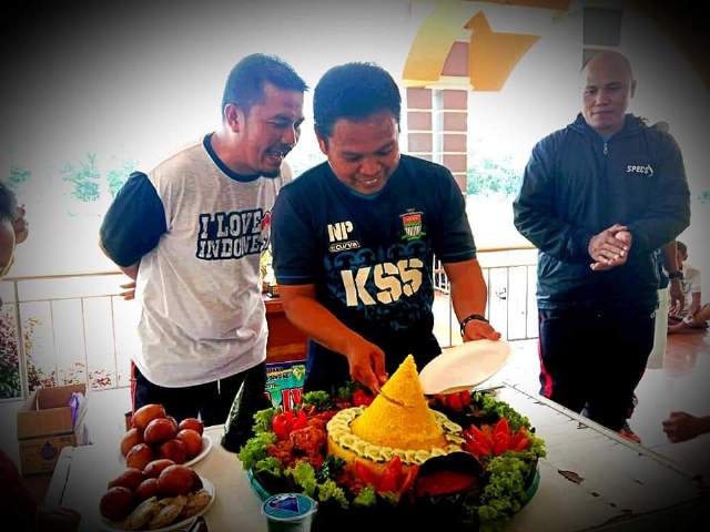 Pelatih kepala SSB KSS Parlin didampingi pelatih memotong nasi tumpeng